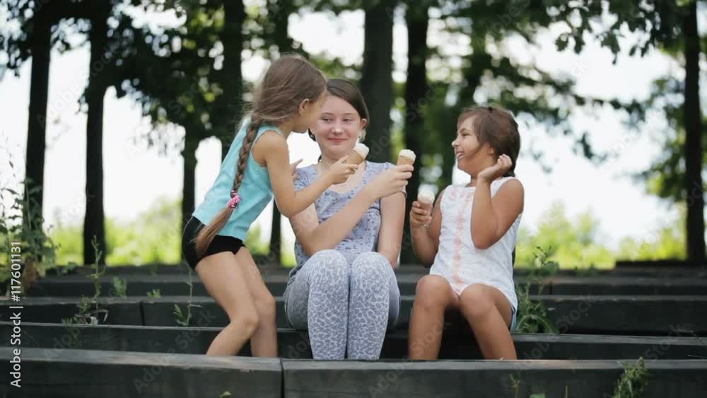 Sisters playing in the daubed ice creams noses together. Girls eating ice cream. Sisters playing in the daubed ice creams noses together. Girls eating ice cream.