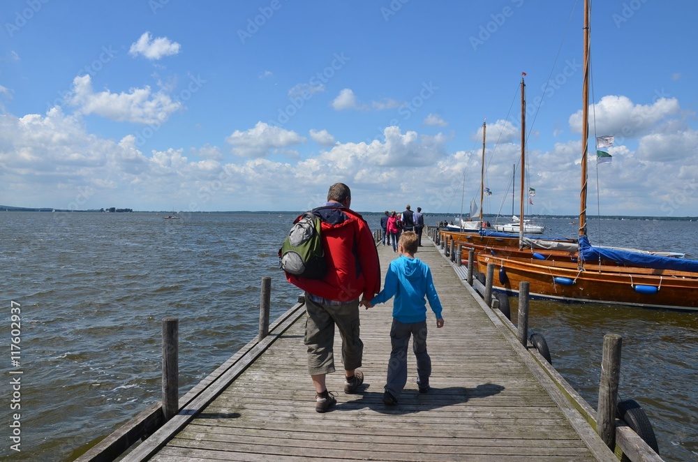 Mann mit Kind Hand in Hand auf Bootssteg am Steinhuder Meer