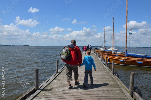 Mann mit Kind Hand in Hand auf Bootssteg am Steinhuder Meer