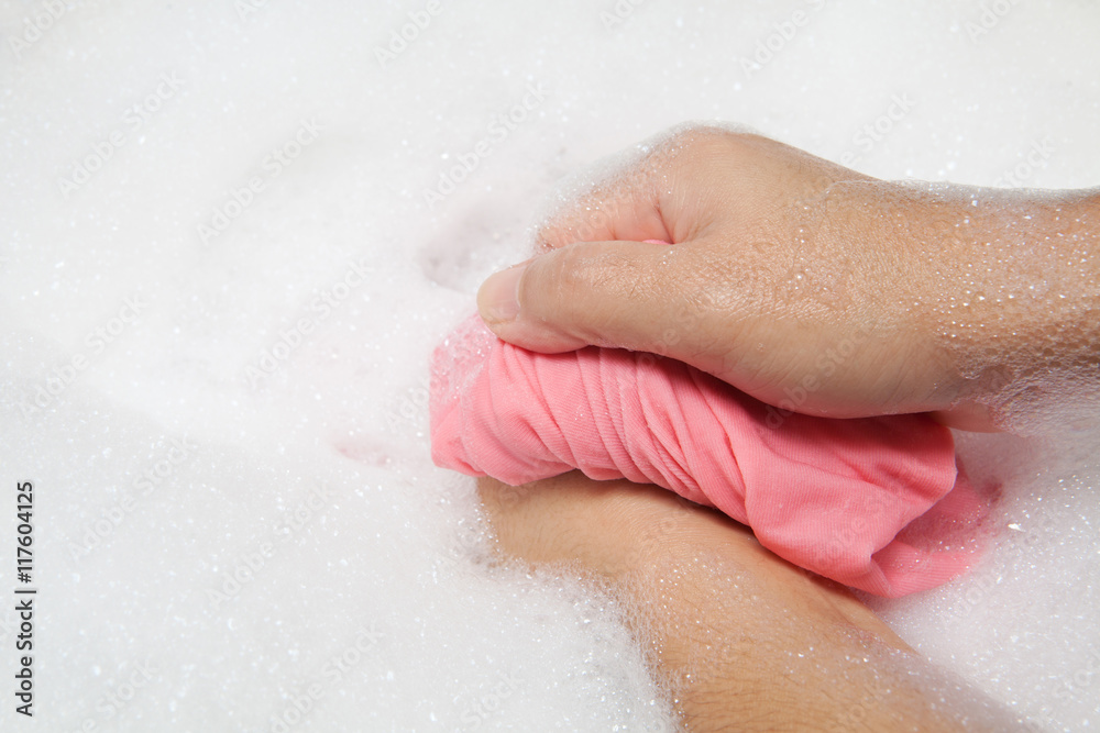 Hand washing clothes with bubble on white basin.