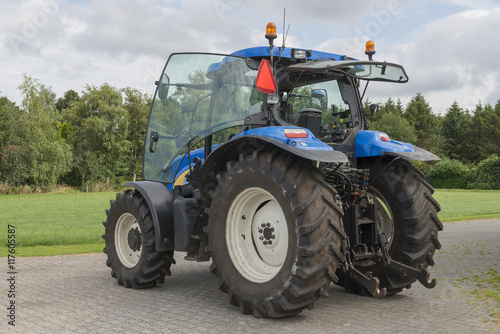 Modern blue tractor on a farmyard.