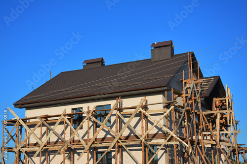 Painting and Plastering Exterior House Scaffolding Facade Wall with New Metal Roofing Outdoor. © bildlove