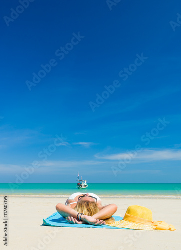 Woman lies on the beach with yellow hat and towel