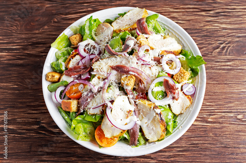 Ceasar salad with grilled chicken fillets, red onion rings, lettuce, orange cherry tomatoes, croutons, grated parmesan cheese, seasoned anchovy 