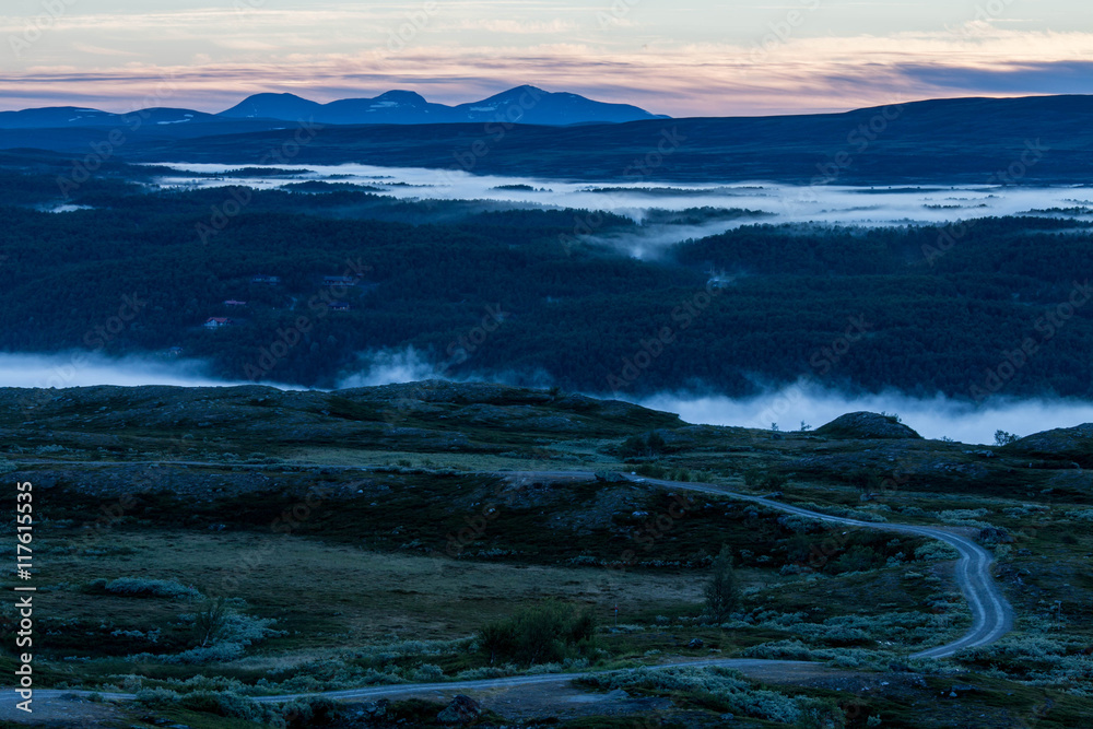 Sunrise in the Swedish mountains, very early during summertime. Morning mist down in the valley.