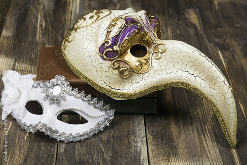 Art concept. Venetian carnival masks on books and wooden surface
