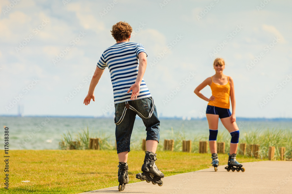 Fototapeta premium Young couple on roller skates riding outdoors