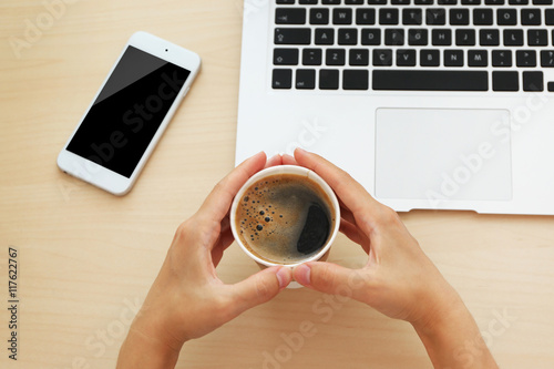 Fototapeta Naklejka Na Ścianę i Meble -  Female hands with laptop, phone and cup of coffee on wooden background