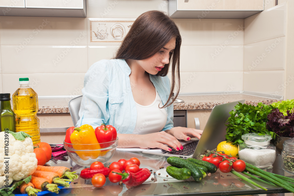 Beautiful girl writes a salad recipe from the laptop