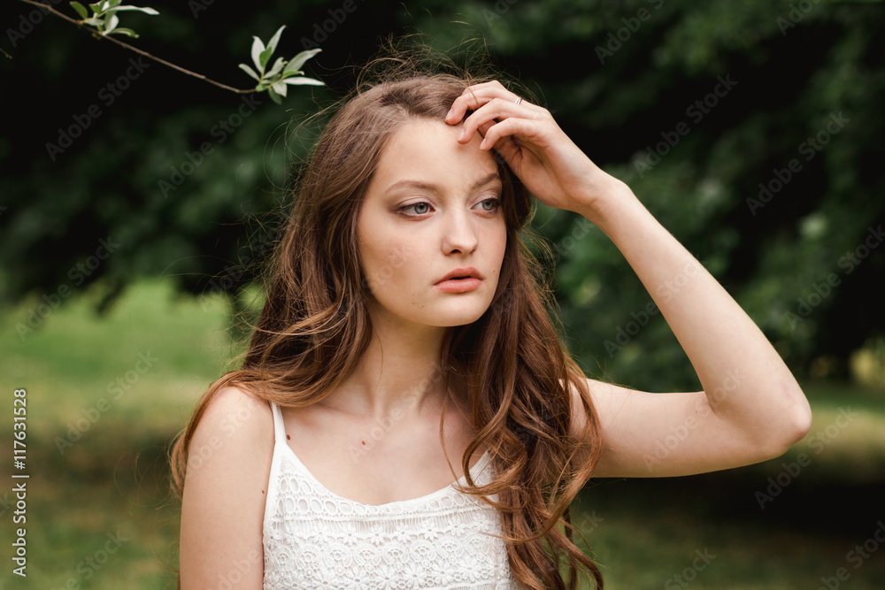 portrait of beautiful young brunette woman in the nature. spring, summer. girl brown hair with blue eyes and with long hair in white summer dress