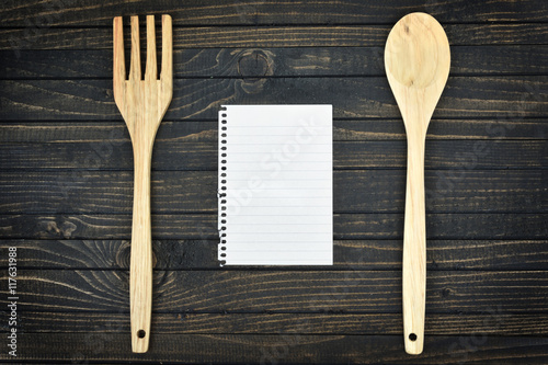 Kitchen utensils and empty page on table