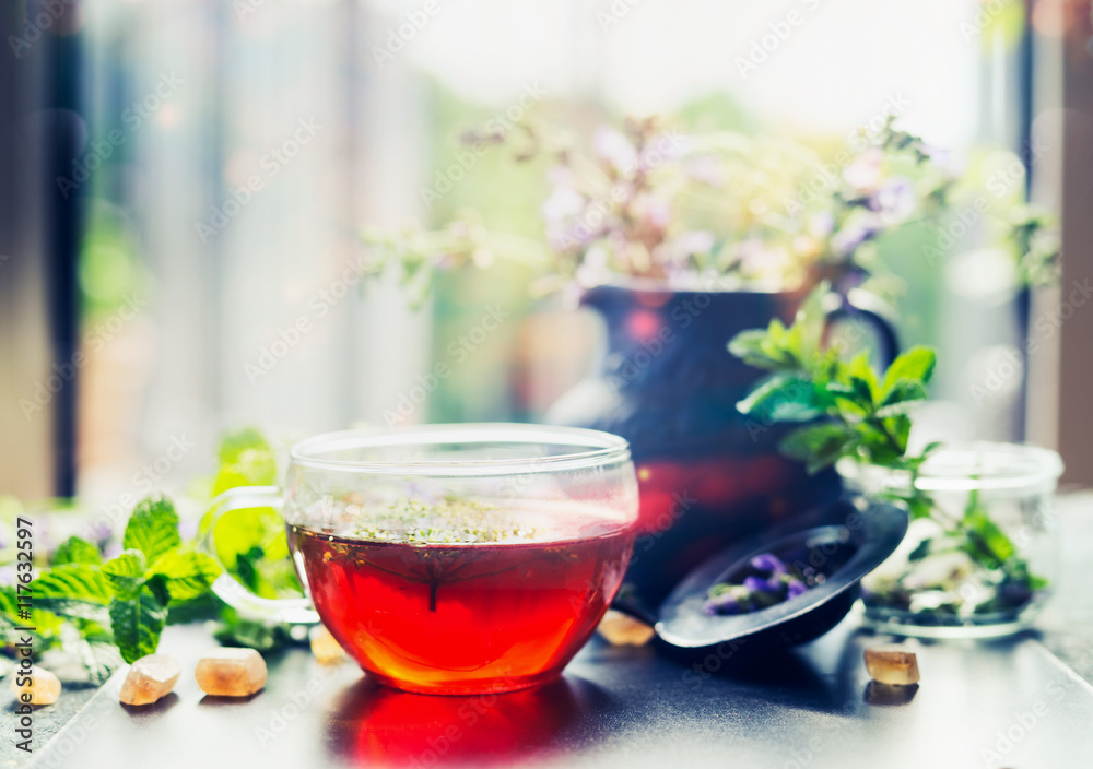 Cup of herbal tea with fresh herbs and sweets on window still Cup of herbal tea with fresh herbs and sweets on window still