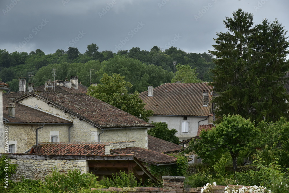 Maisons rustiques de Champagne-et-Fontaine au milieu de la nature luxuriante sous un ciel gris au Périgord Vert
