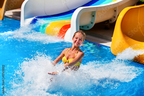 Child on water slide at water park . Child girl in water splashes.