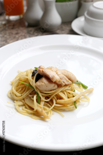 Puff yellow noodles with chicken meat on white dish.