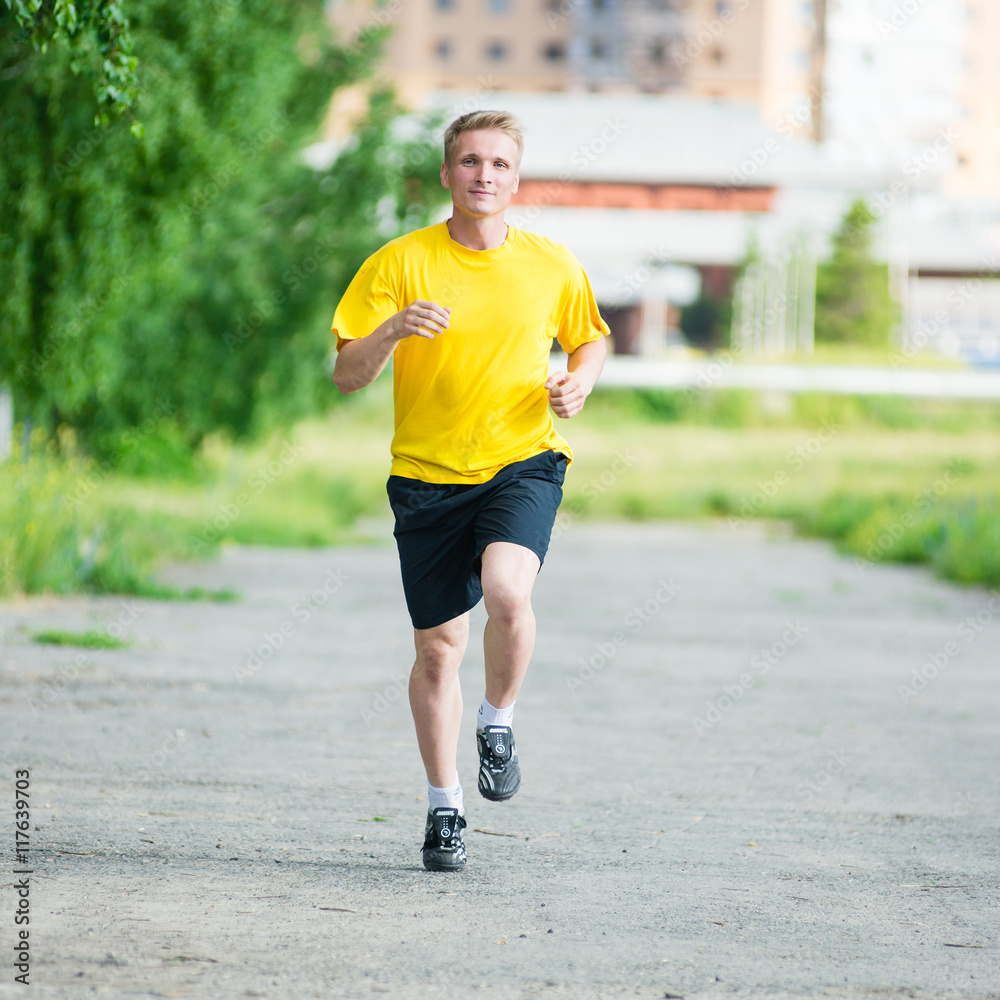 Running man jogging in city street park at beautiful summer day. Sport fitness model caucasian ethnicity training outdoor. Running man jogging in city street park at beautiful summer day. Sport fitness model caucasian ethnicity training outdoor.