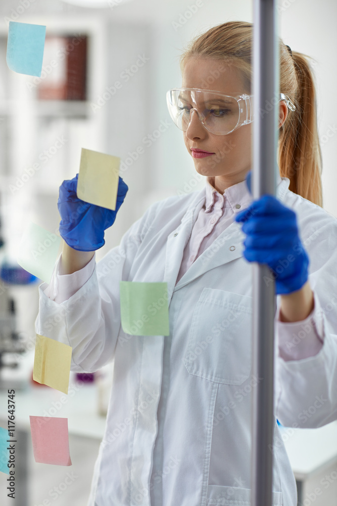 female chemist writing on sticky notes. female chemist writing on sticky notes.