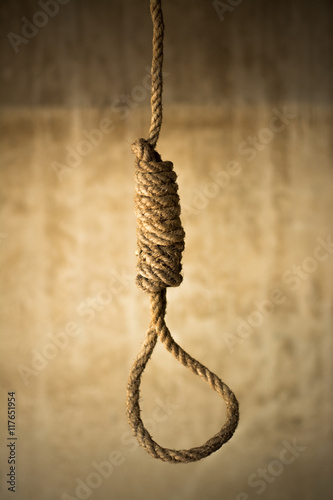 Noose in prison and wall grunge grain texture,Loop of old rope on wall background, Suicide concept Image in Studio with vignette lighting and copy space.