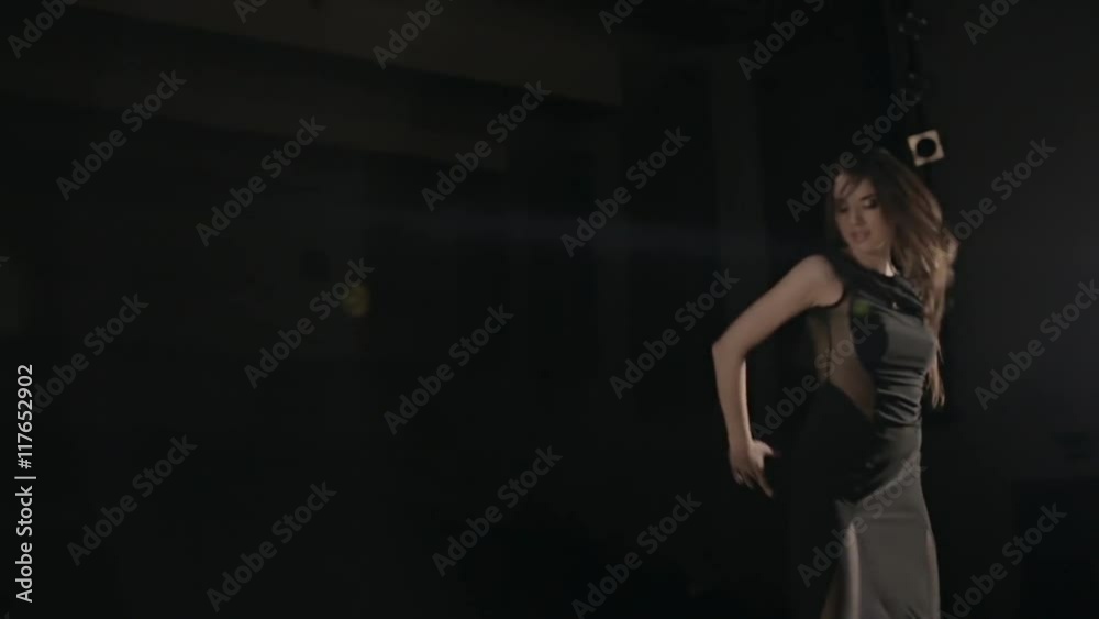 Young woman in black dress dancing under the spotlight Young woman in black dress dancing under the spotlight