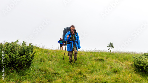 Two hikers with backpacks hiking in Carpathian mountains, summertime journey