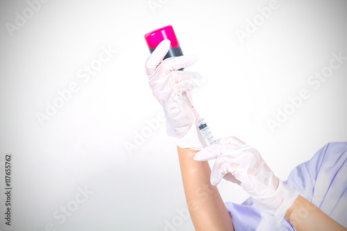 Medical gloved hand holding syringe with red blood liquid and a