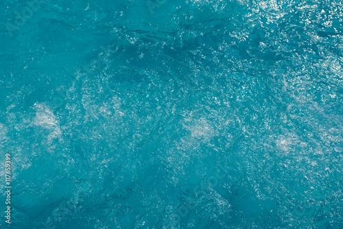 Blue water surface with sun reflection in swimming pool