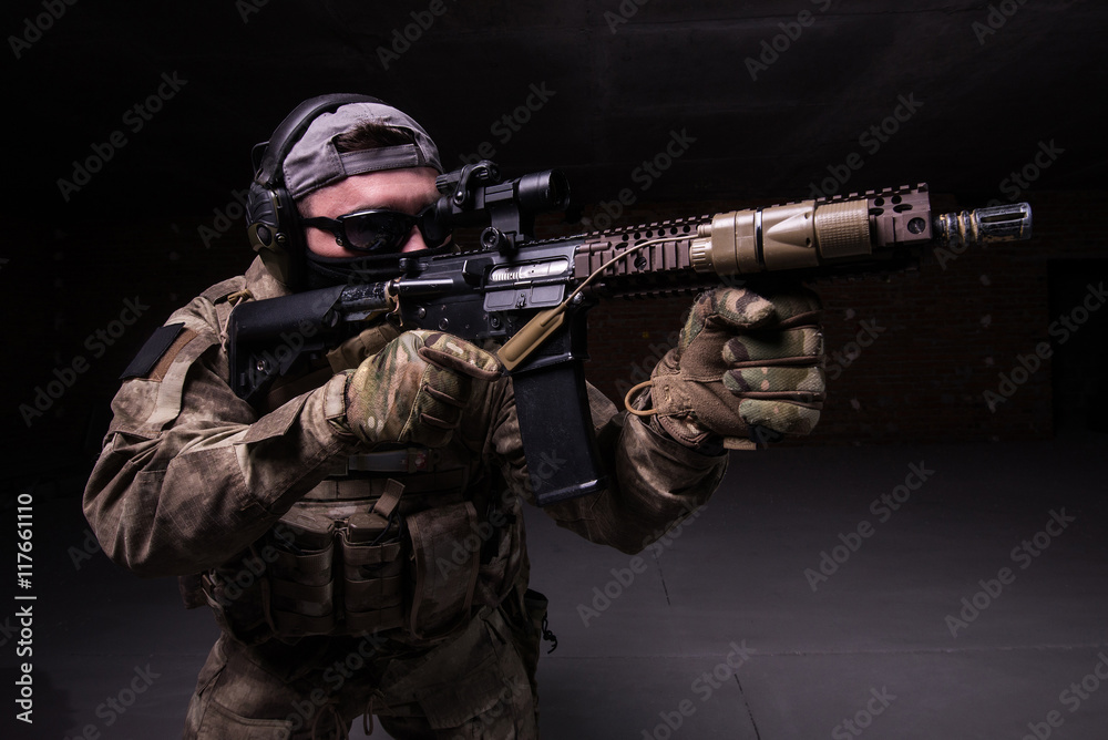 Spec ops soldier in mask with gun/Man with rifle in dark glasses and black mask aiming at target from assault rifle Spec ops soldier in mask with gun/Man with rifle in dark glasses and black mask aiming at target from assault rifle