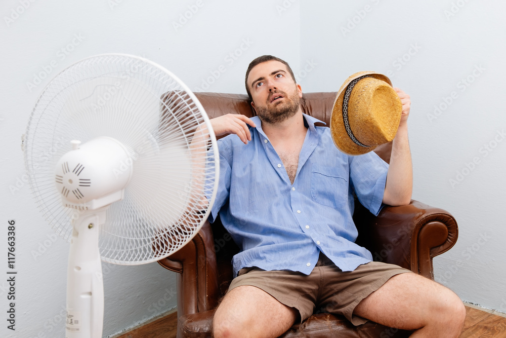 Flushed man feeling hot in front of a fan - obrazy, fototapety, plakaty 