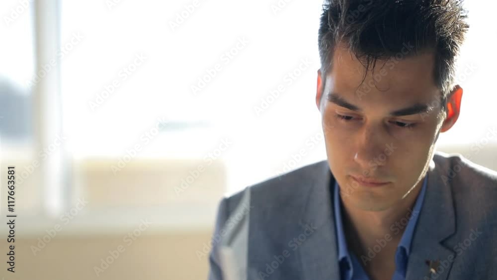Young and handsome male is reading document sitting in office. Young and handsome male is reading document sitting in office.