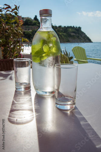 Bottle of cold mint water with two glasses on a table