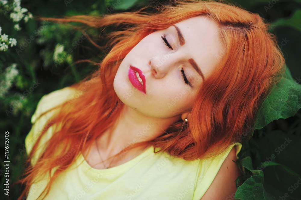 Naklejka premium Portrait of a young girl with long red hair with his eyes closed