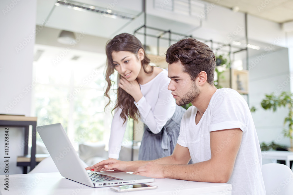 Two young business people in casual wear looking at the laptop. Two young business people in casual wear looking at the laptop.
