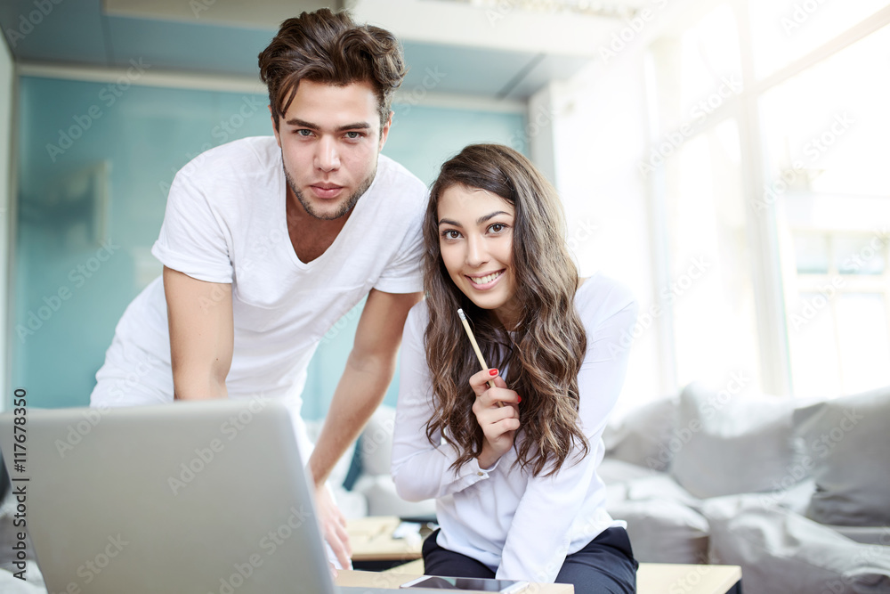 Two young business people in casual wear looking at the laptop.