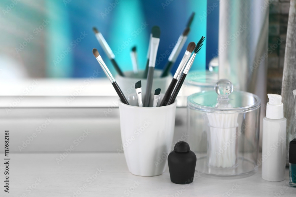 Cosmetic brushes in cup on light dressing table Cosmetic brushes in cup on light dressing table