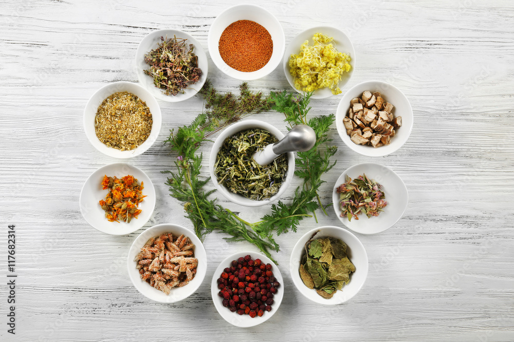 Natural flower and herb selection in  bowls on wooden background