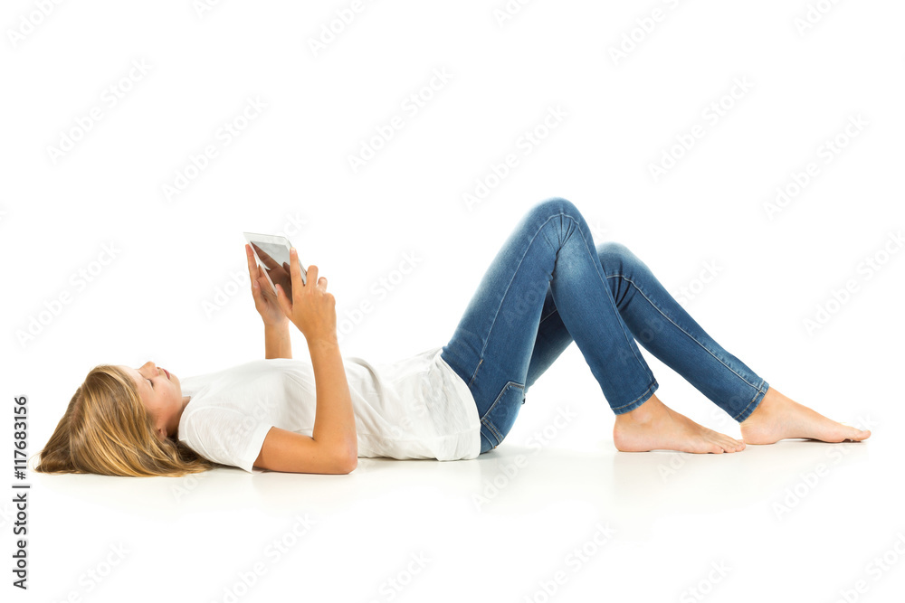 Young girl lying on the floor using tablet pc over white backgro Young girl lying on the floor using tablet pc over white backgro