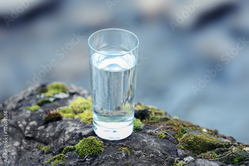 Glass of water on blurred river background