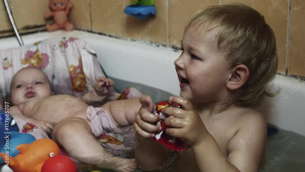 Happy little boy play with toys in bathtub. Baby swim in cradle. Water. Children. Childhood Happy little boy play with toys in bathtub. Baby swim in cradle. Water. Children. Childhood