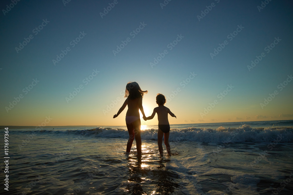 boy and girl on the sea at sunset