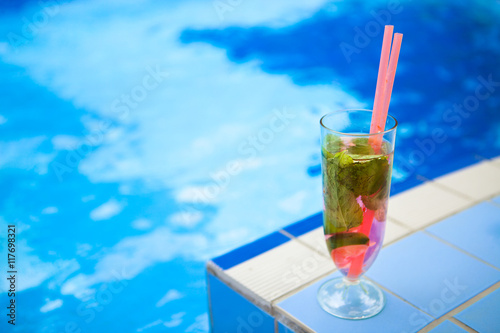 Glass of refreshment drink with strawberry mojito on a pool side