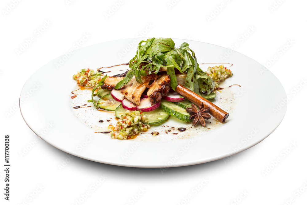 vegetable salad with octopus decorated with cinnamon stick and Dittany on a round plate on a white background vegetable salad with octopus decorated with cinnamon stick and Dittany on a round plate on a white background