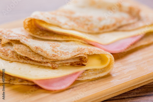 pancakes with ham and cheese on a wooden board