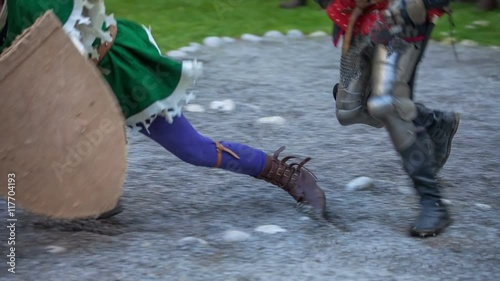 A knight is running and then he is knocking anoter knight down so that he falls on the ground. Close-up shot.
 photo