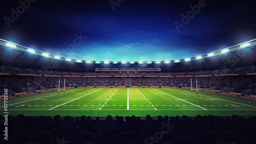 illuminated modern rugby stadium with spectators and green grass
