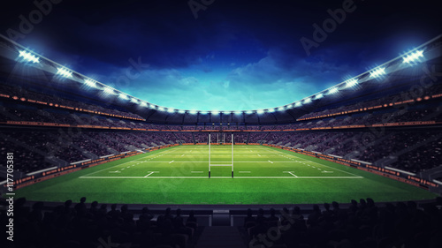 illuminated rugby stadium with spectators and green grass