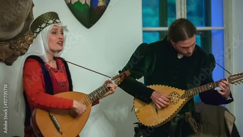 Two members of a royal family are playing a tambura and the princess is singing with it, too. Close-up shot.
 photo