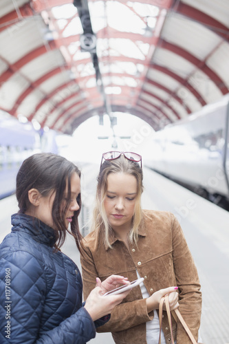 Young women using cell phone at railway station photo