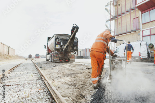 Rear view of manual worker laying asphalt at construction site photo