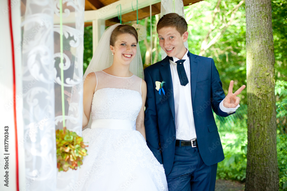 Laughing bride and groom stand on a white porch