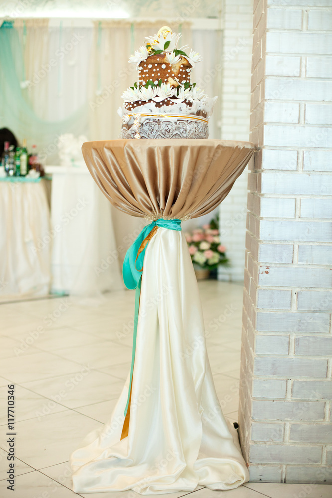 Wedding bread decorated with white flowers stands on the high ro